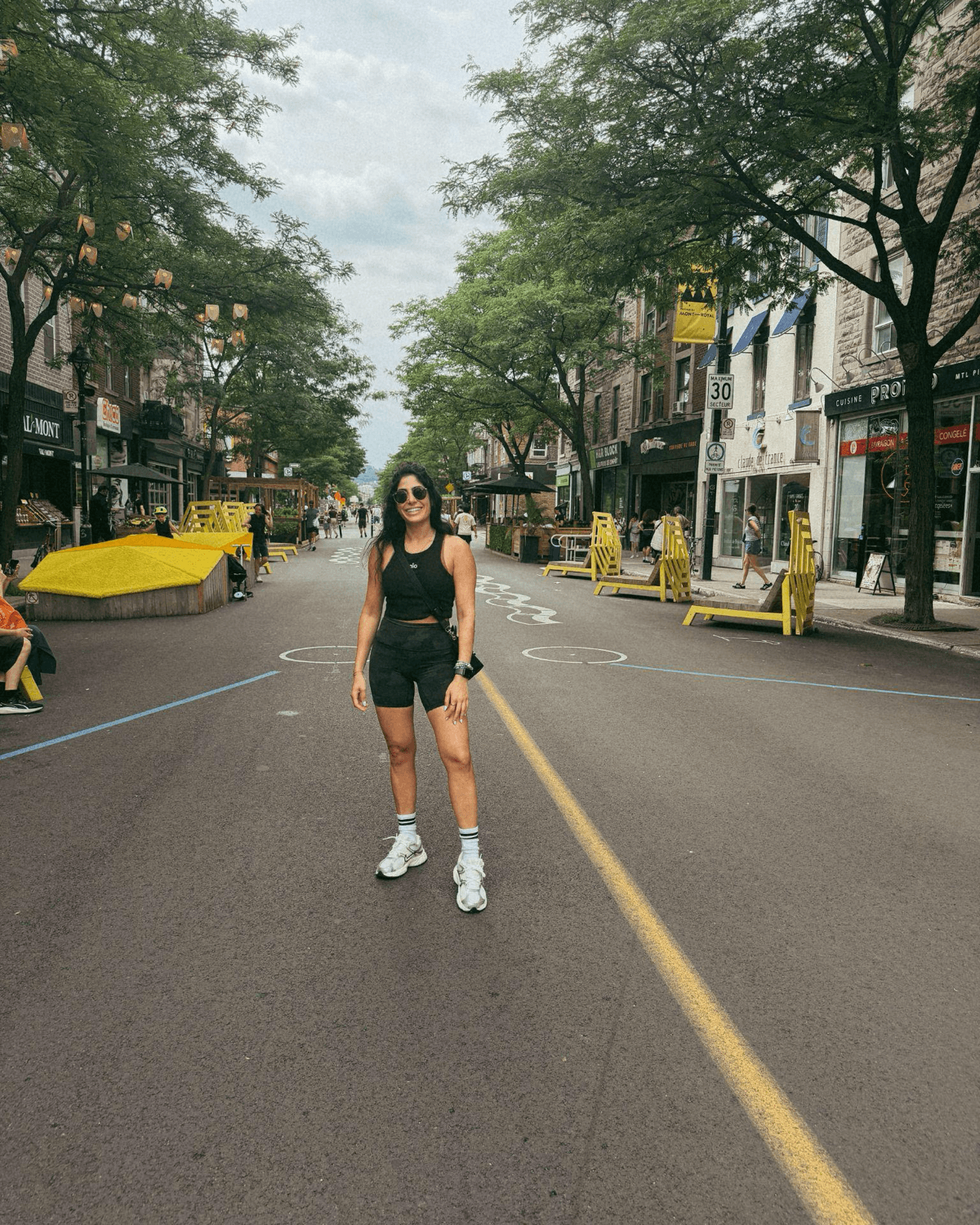 Fabienne Abi-Ad, founder of The Rewrite, standing in the middle of a tree-lined city street on a summer day
